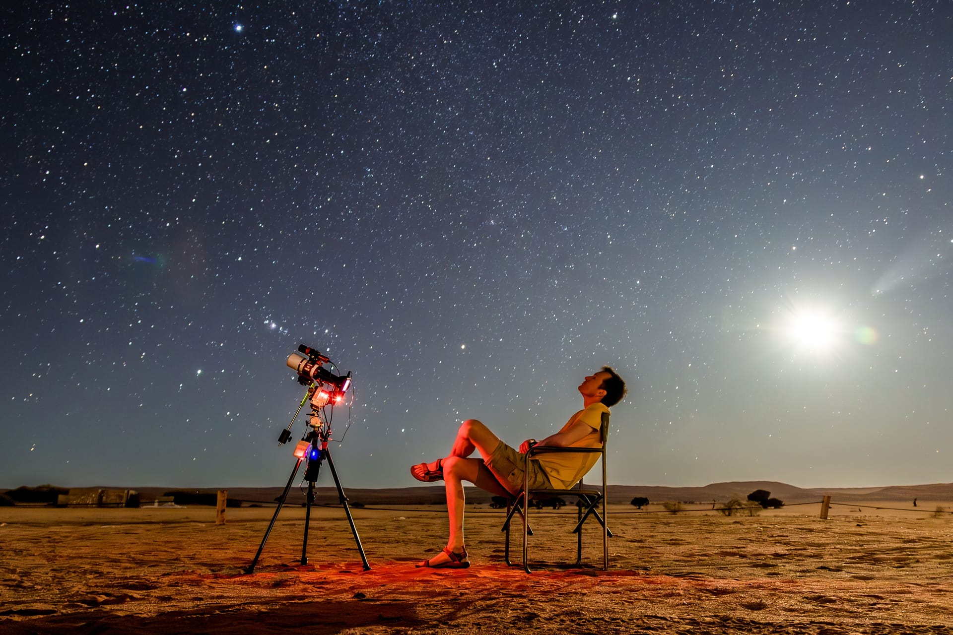 Namibia: Ein Mann mit Teleskop beobachtet, wie die Nacht hereinbricht.