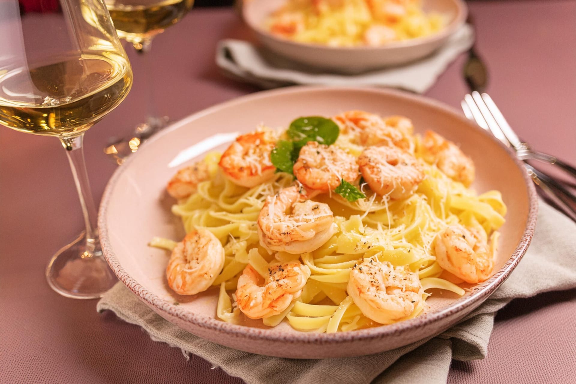 A shrimp pasta dish served with white wine on a dining table.