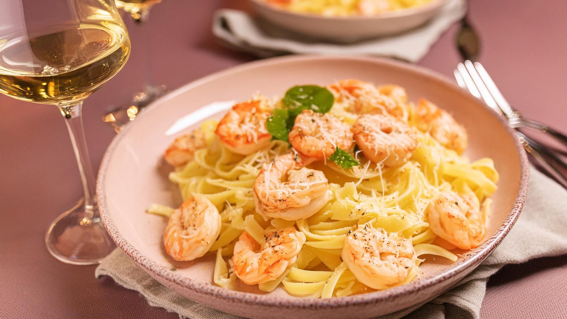 A shrimp pasta dish served with white wine on a dining table.