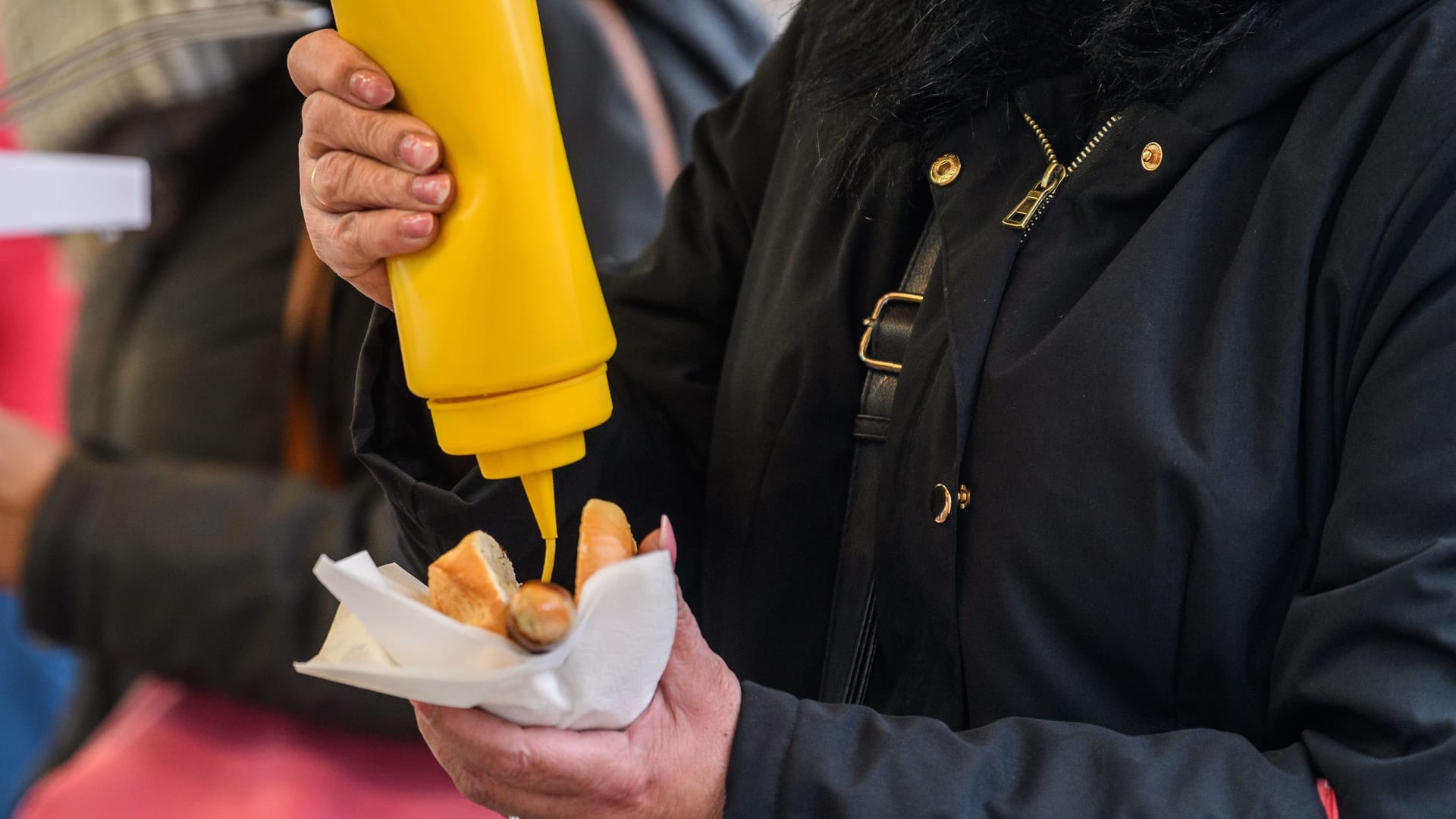 Eine Frau drückt Senf auf ihre Wurst (Symbolbild): Ein Stand auf dem Bremer Freimarkt fiel negativ auf.