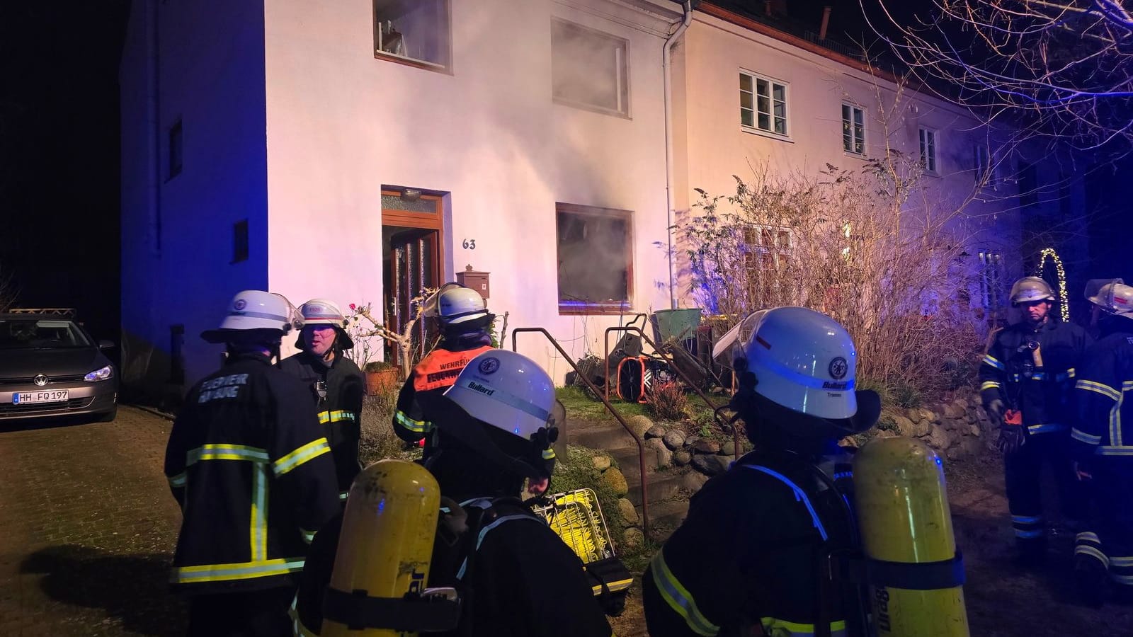 Einsatzkräfte der Feuerwehr vor dem Haus: Es ist nach dem Feuer im Wohnzimmer unbewohnbar.