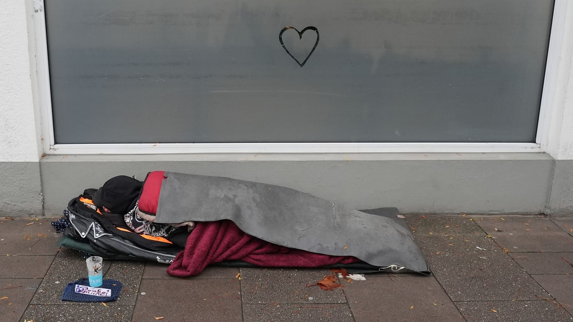 Ein Obdachloser liegt auf dem Gehweg (Symbolbild): Ein Bericht der Bundesregierung legt neue Zahlen offen.