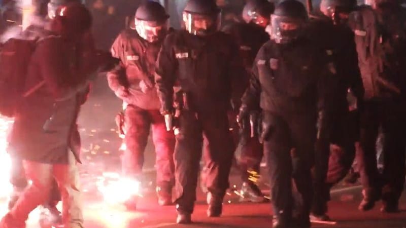 Einsatzkräfte der Polizei stehen in der Silvesternacht zwischen brennendem Feuerwerk in Neukölln.