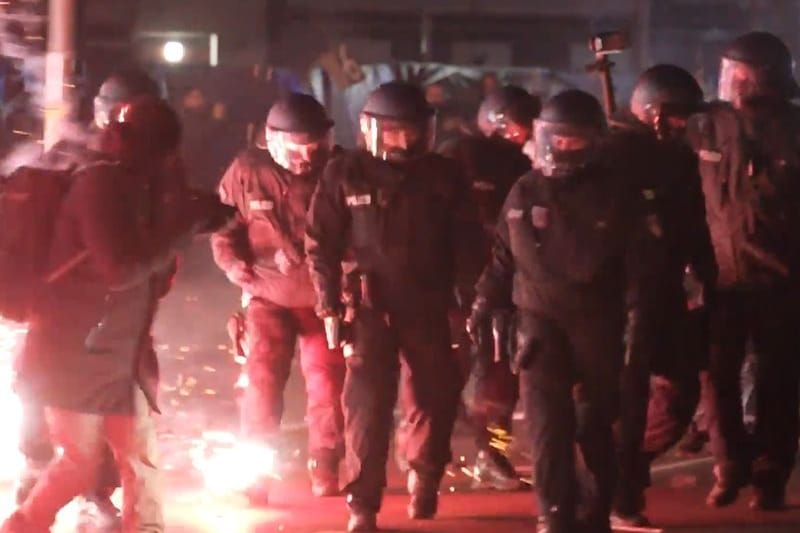 Einsatzkräfte der Polizei stehen in der Silvesternacht zwischen brennendem Feuerwerk in Neukölln.