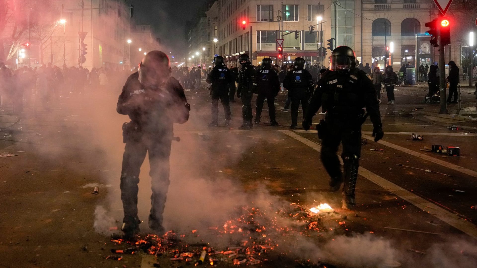 Polizeikräfte vor einem glühenden Feuerwerkhaufen in Berlin. Die Silvesternacht bedeutet für Polizei, Feuerwehr und Ärzte einen tagelangen Ausnahmezustand.