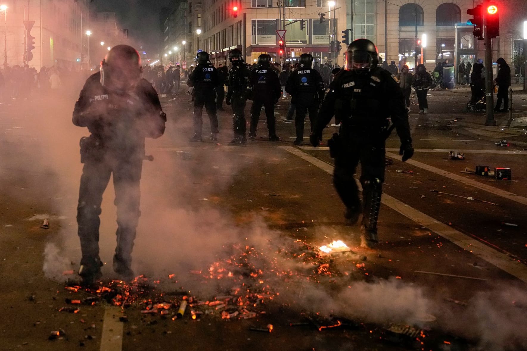 Polizeikräfte vor einem glühenden Feuerwerkhaufen in Berlin. Die Silvesternacht bedeutet für Polizei, Feuerwehr und Ärzte einen tagelangen Ausnahmezustand.