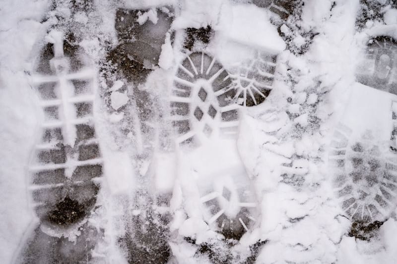 Spuren von Fußgängern sind im Schnee auf einem Bürgersteig zu sehen (Symbolbild).