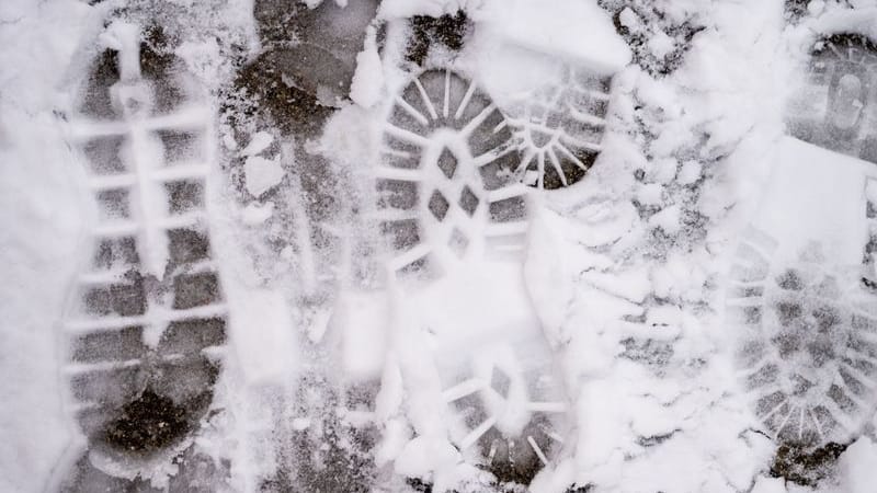 Spuren von Fußgängern sind im Schnee auf einem Bürgersteig zu sehen (Symbolbild).