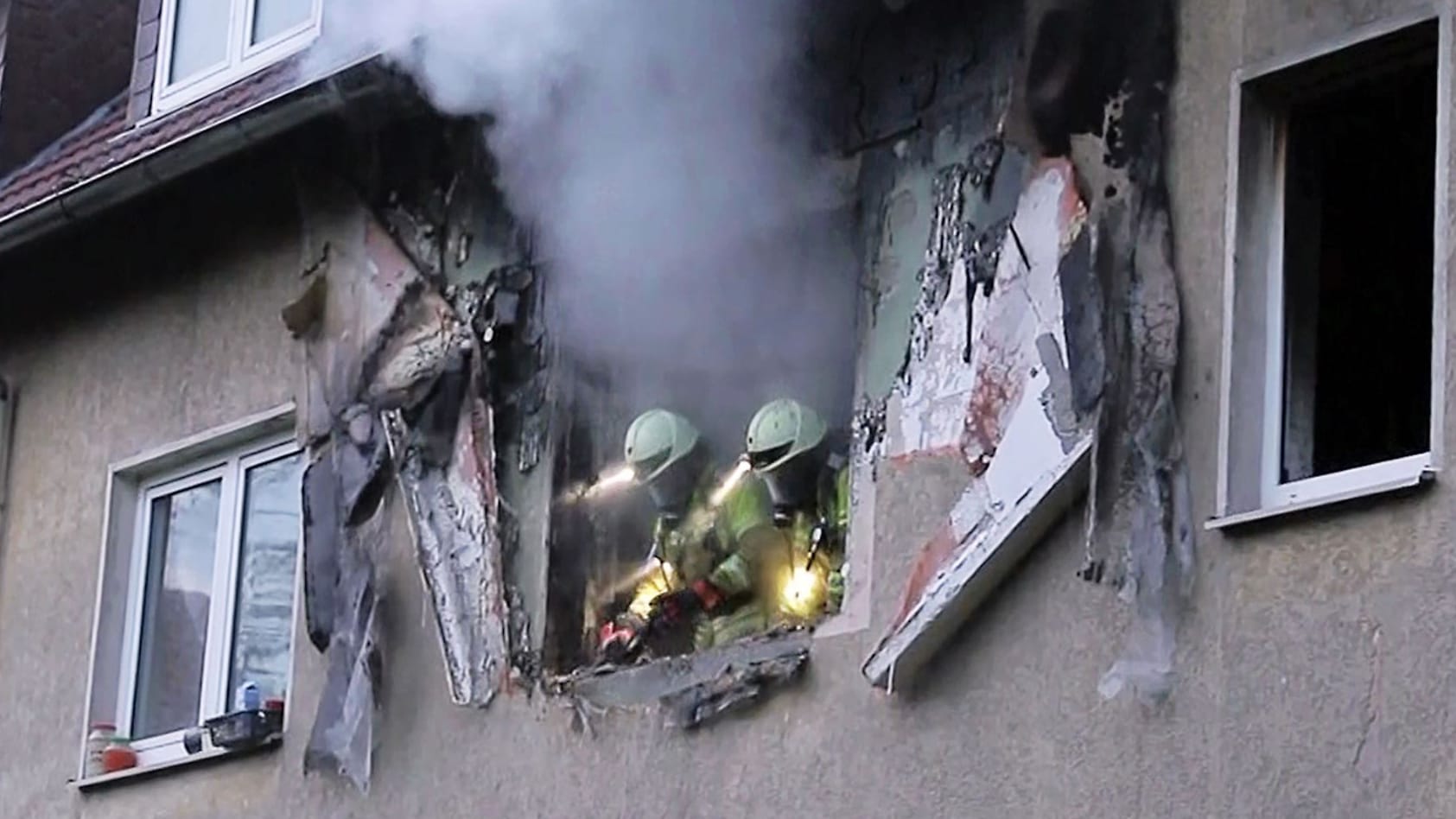 Einsatzkräfte der Feuerwehr schauen aus einem zerstörten Fenster: Beim Eintreffen der Feuerwehr hätten die Flammen bereits auf den Dachstuhl übergegriffen.