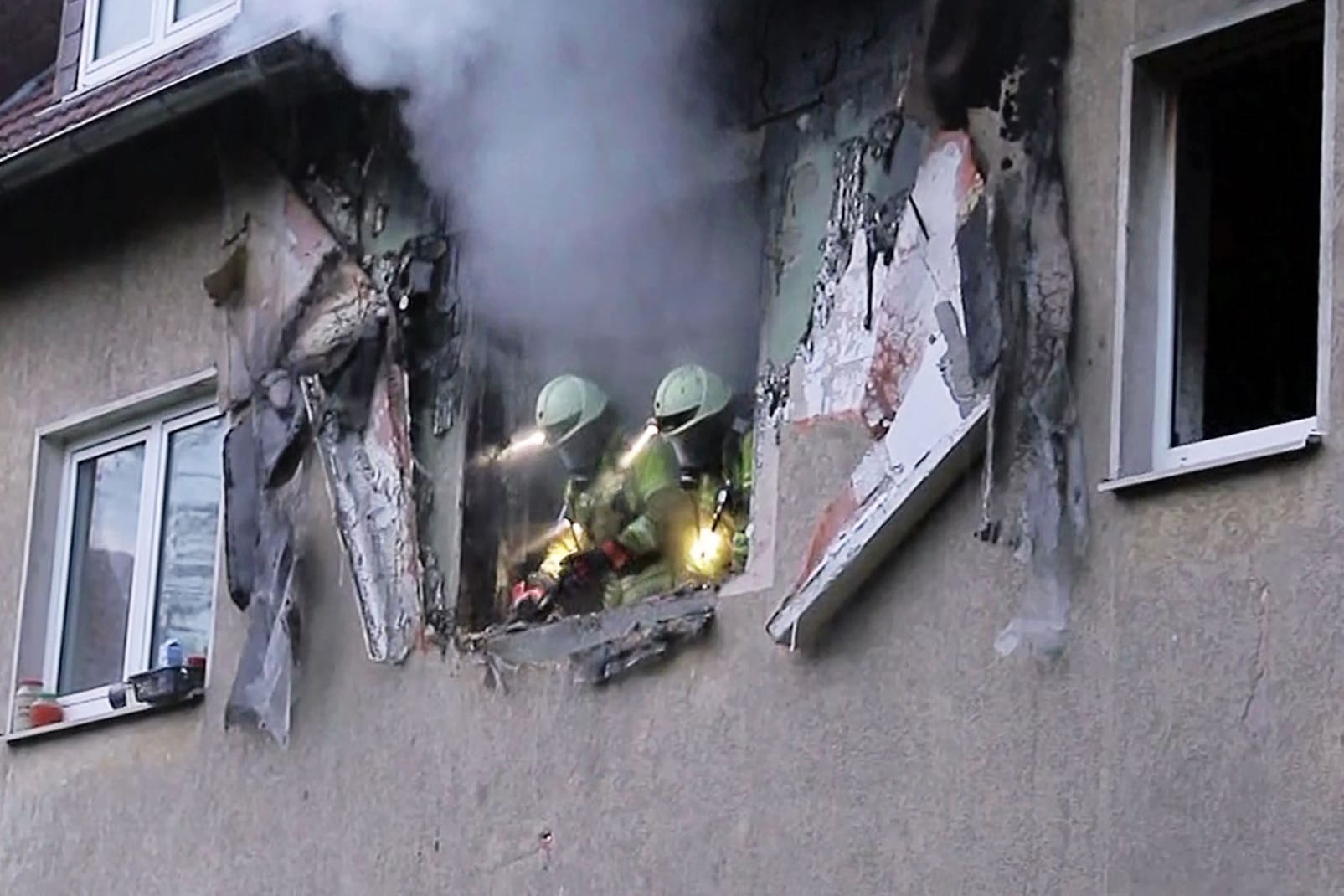 Einsatzkräfte der Feuerwehr schauen aus einem zerstörten Fenster: Beim Eintreffen der Feuerwehr hätten die Flammen bereits auf den Dachstuhl übergegriffen.