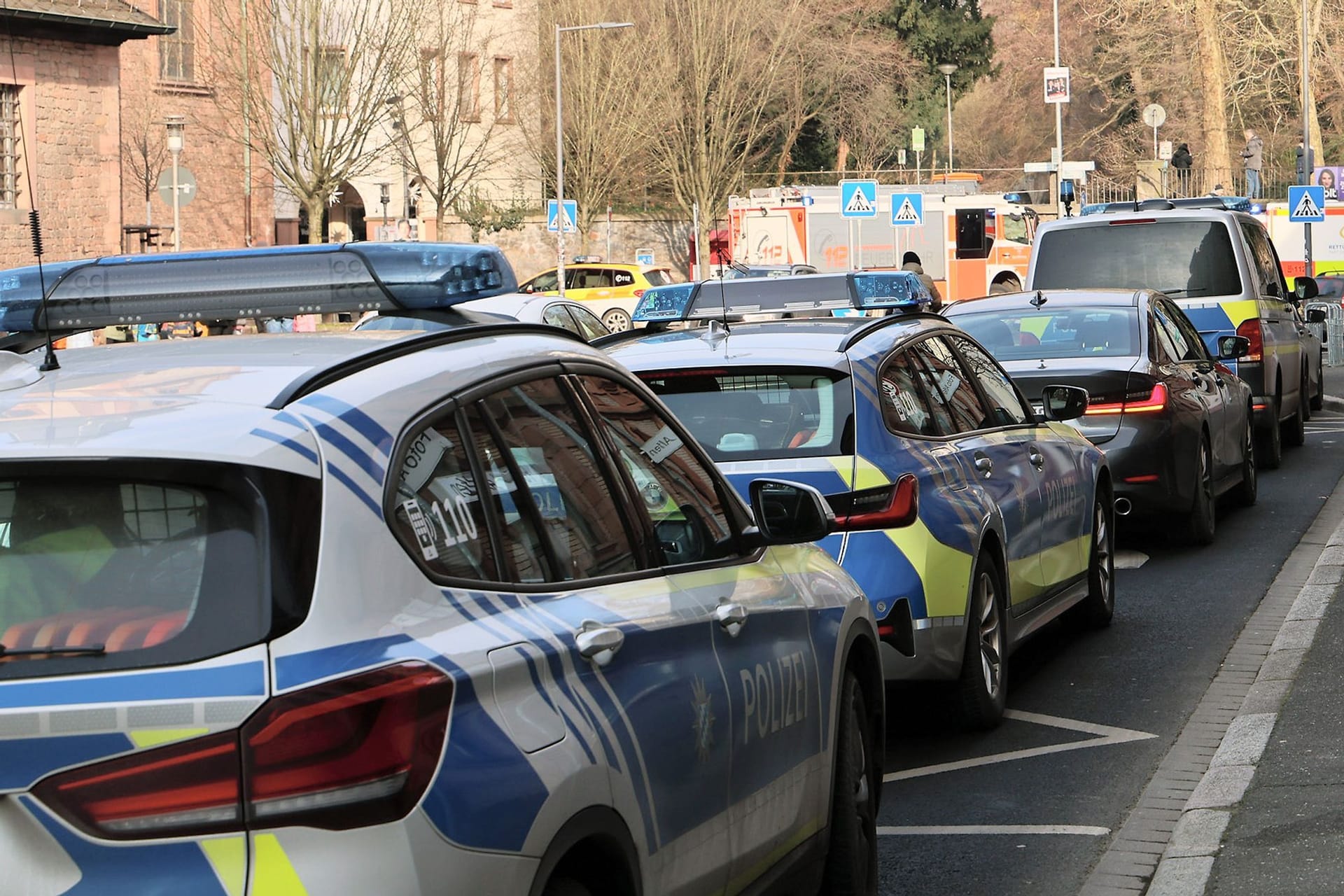 Einige Polizeifahrzeuge und Rettungswagen stehen in der Nähe eines Tatortes in Aschaffenburg: Zwei Menschen wurden getötet, darunter ein Kind.