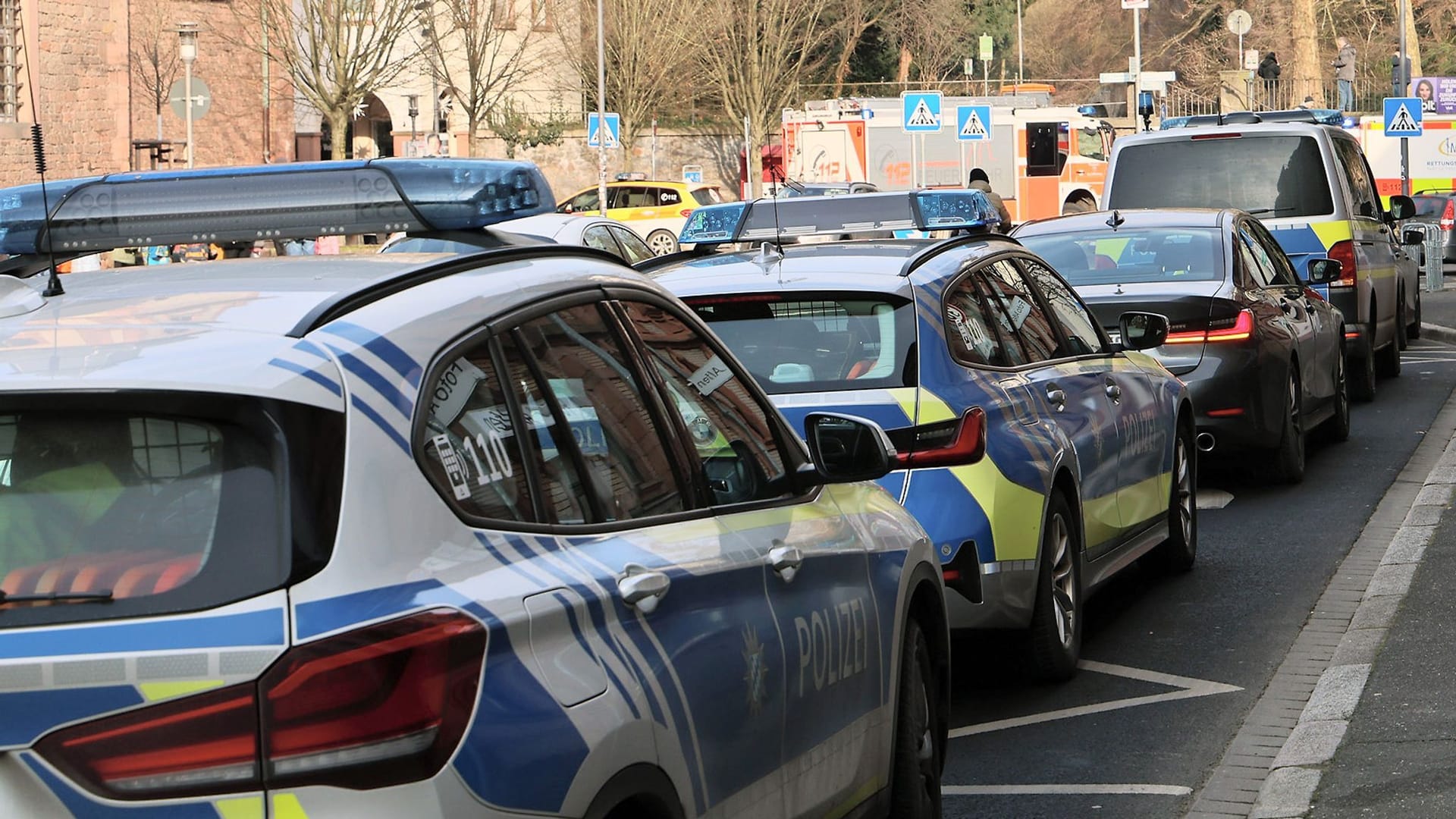 Einige Polizeifahrzeuge und Rettungswagen stehen in der Nähe eines Tatortes in Aschaffenburg: Zwei Menschen wurden getötet, darunter ein Kind.