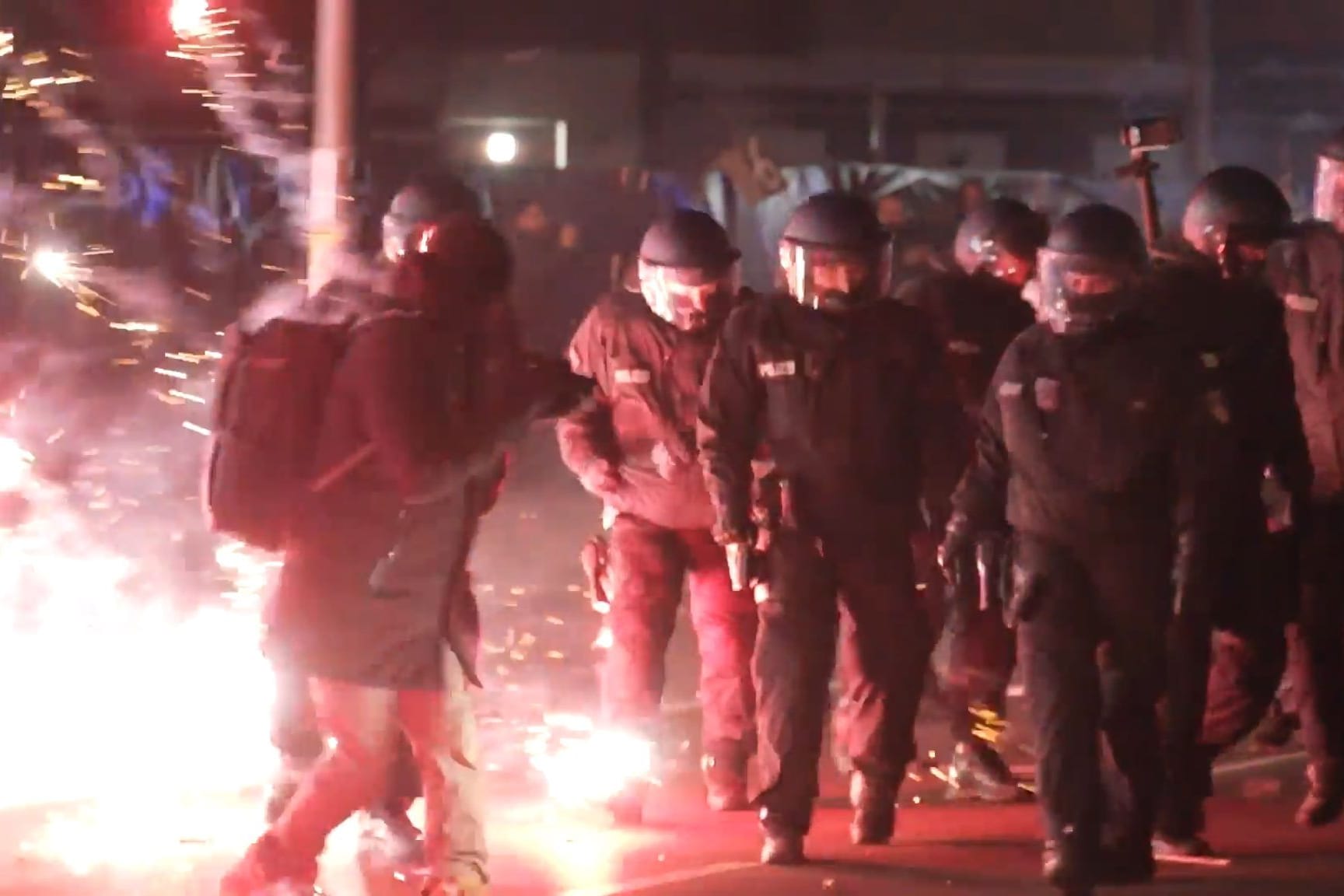 ARCHIV - 01.01.2025, Berlin: Einsatzkräfte der Polizei stehen in der Silvesternacht zwischen brennendem Feuerwerk in Neukölln.