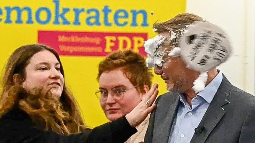 Eine Frau wirft Christian Lindner eine Seifentorte ins Gesicht.