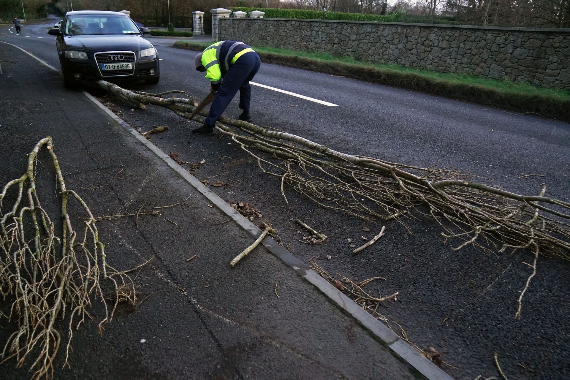 Ein Mann zersägt in Irland einen auf die Straße gefallenen Baum.