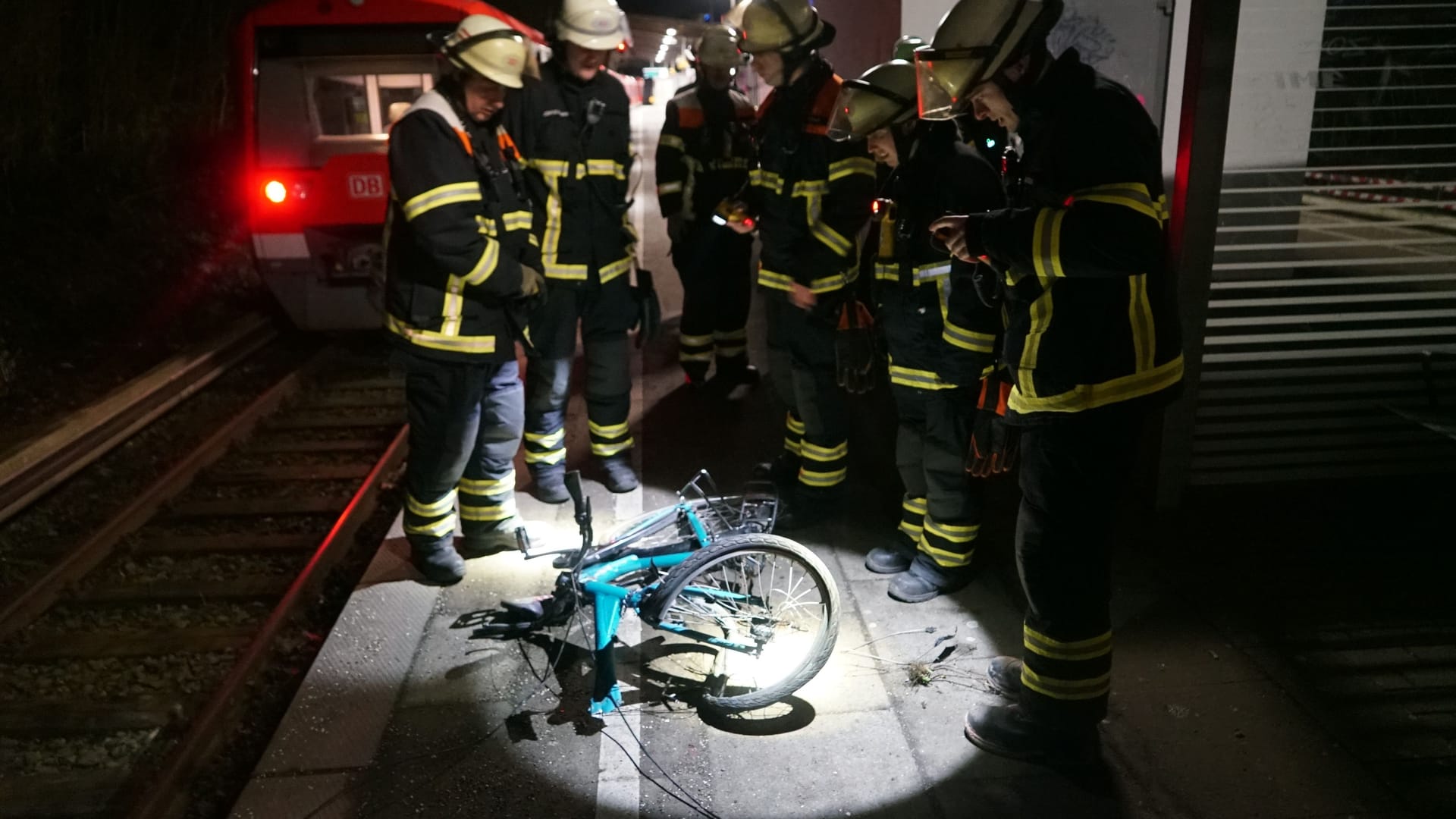 Feuerwehrleute um das demolierte Rad des Fahrradfahrers.