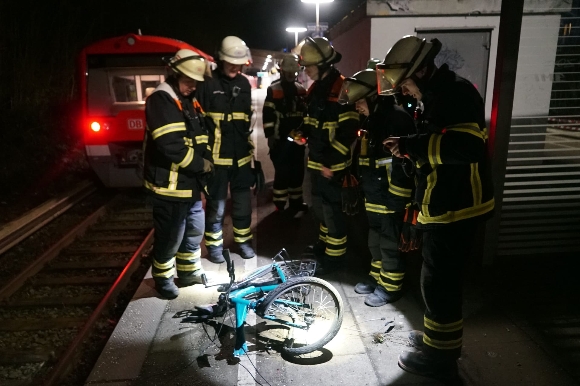 Feuerwehrleute um das demolierte Rad des Fahrradfahrers.