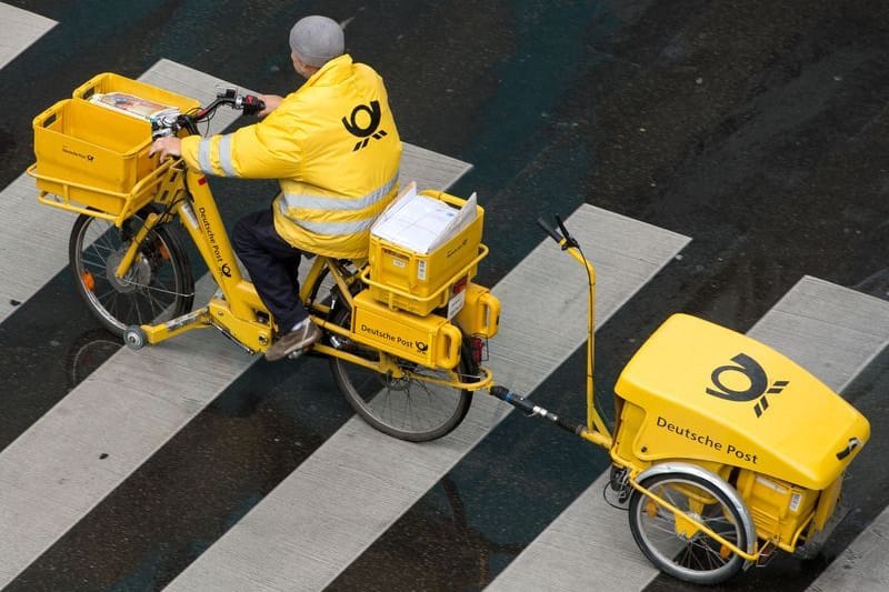 Ein Briefträger der Deutschen Post fährt mit einem Fahrrad (Symbolbild): Am Dienstag streiken Postboten bundesweit.