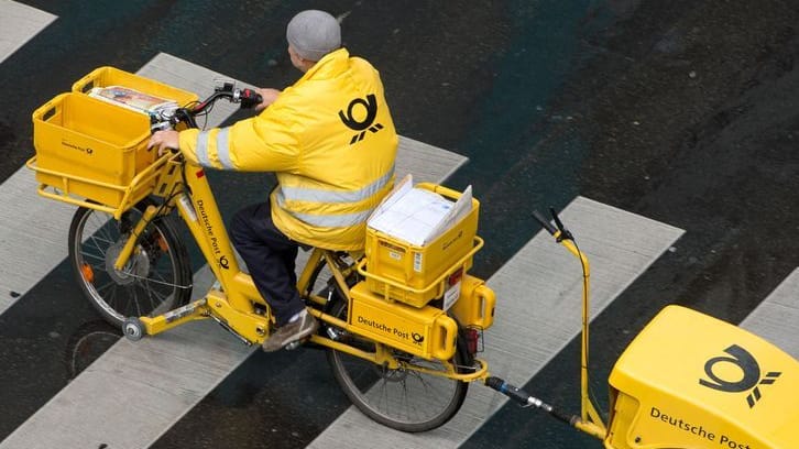 Ein Briefträger der Deutschen Post fährt mit einem Fahrrad (Symbolbild): Am Dienstag streiken Postboten bundesweit.