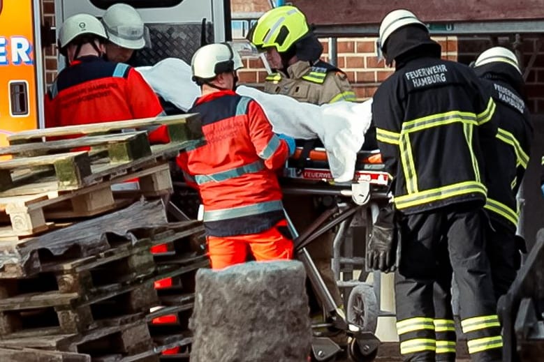 Rettungskräfte kümmern sich um den schwer verletzten Arbeiter: Was zu dem Unfall in Rothenburgsort geführt hat, ist unklar.