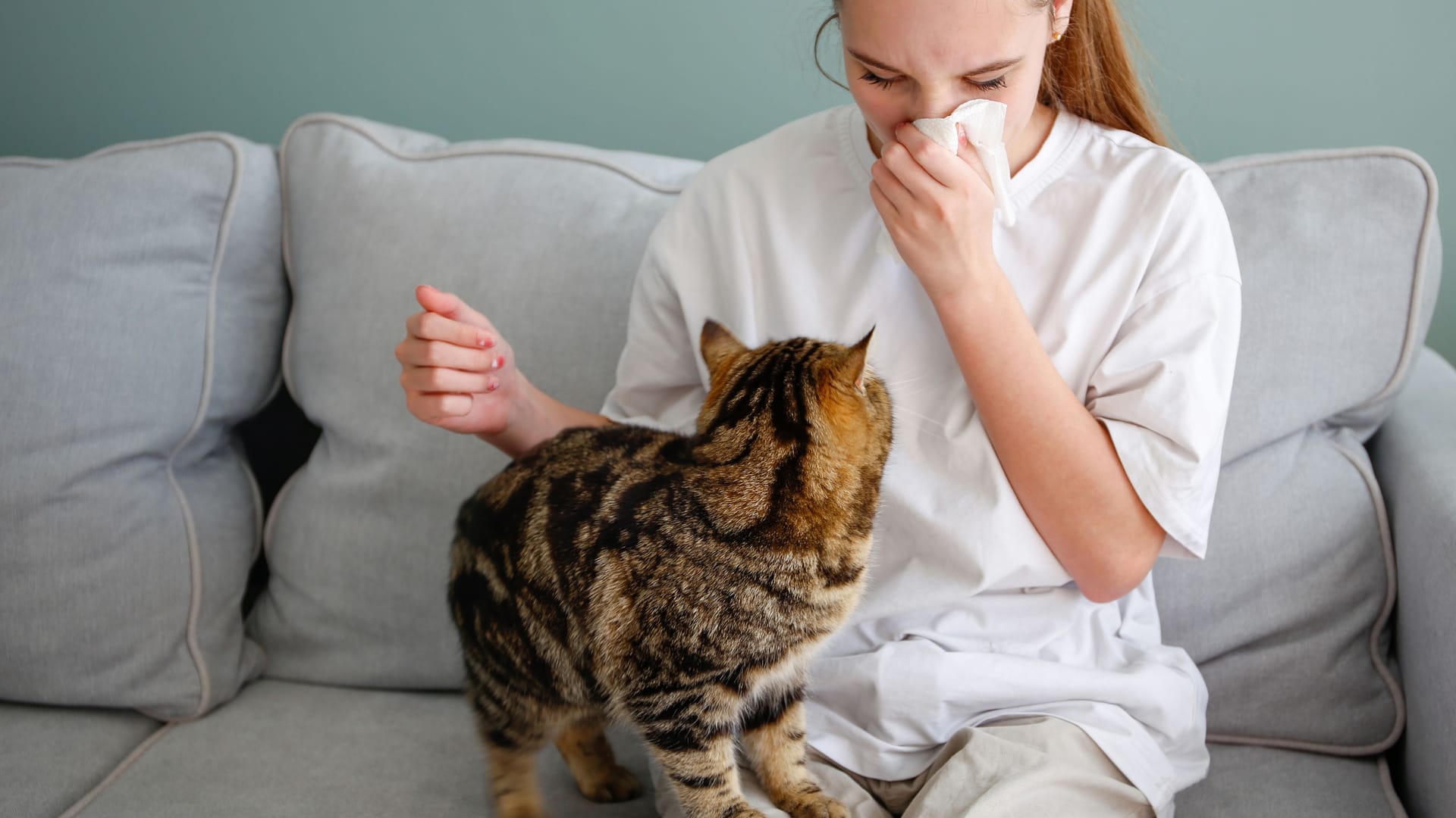 Frau mit Katze putzt sich die Nase