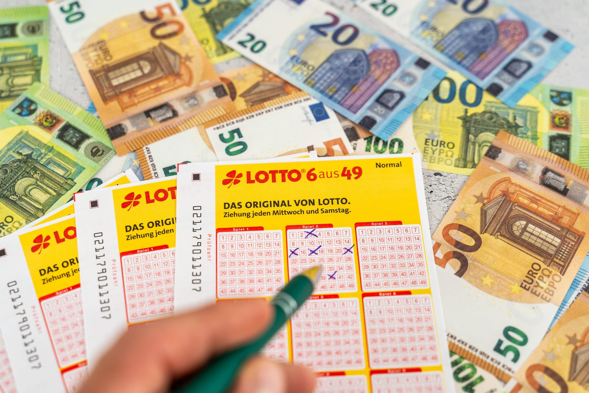 Lotto-Spielscheine vor einigen Geldscheinen. (Symbolfoto)