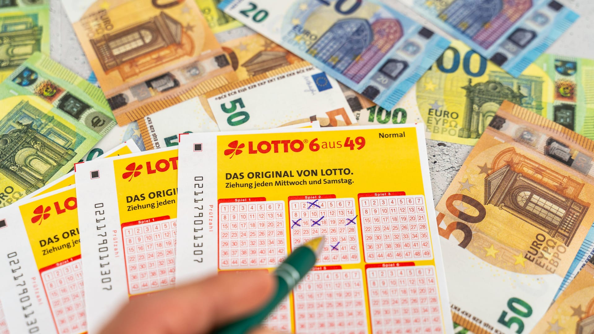 Lotto-Spielscheine vor einigen Geldscheinen. (Symbolfoto)