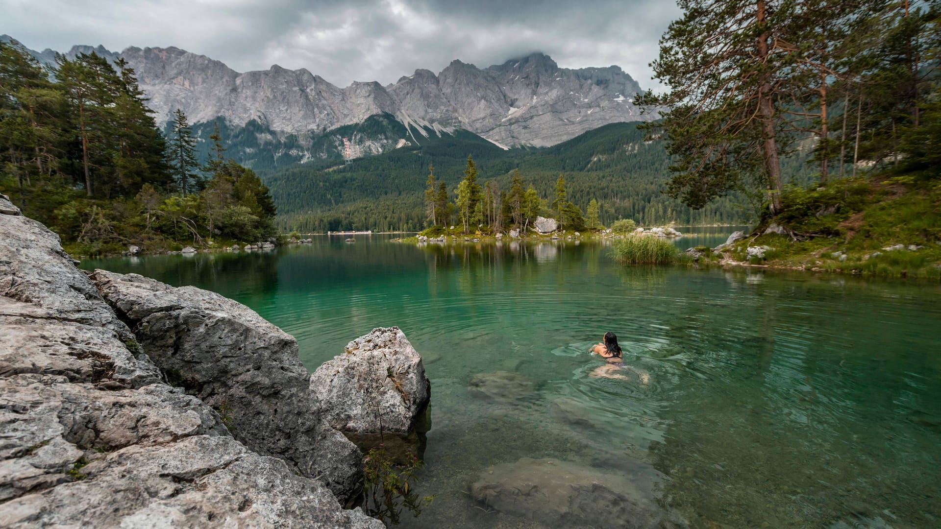 Grünes, klares Wasser: Eine Frau beendet ihre Wanderung mit einem Bad im Eibsee (Bayern).