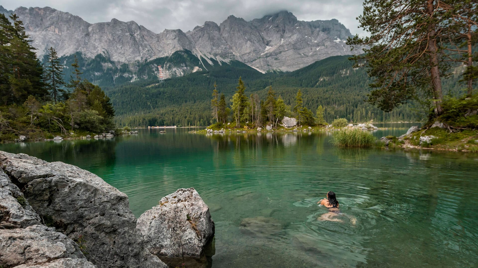 Grünes, klares Wasser: Eine Frau beendet ihre Wanderung mit einem Bad im Eibsee (Bayern).