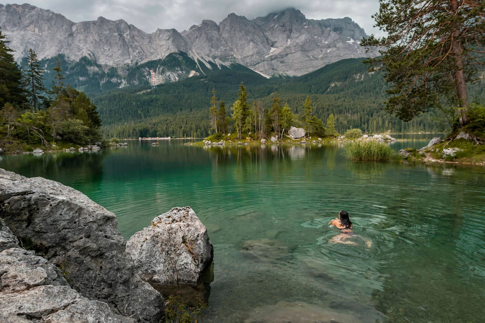 Grünes, klares Wasser: Eine Frau beendet ihre Wanderung mit einem Bad im Eibsee (Bayern).