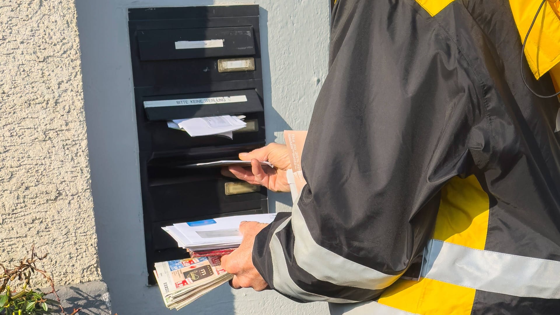 Ein Postbote wirft Briefe in den Briefkasten eines Hauses (Symbolbild): Nicht jeder möchte Werbung für Parteien erhalten.