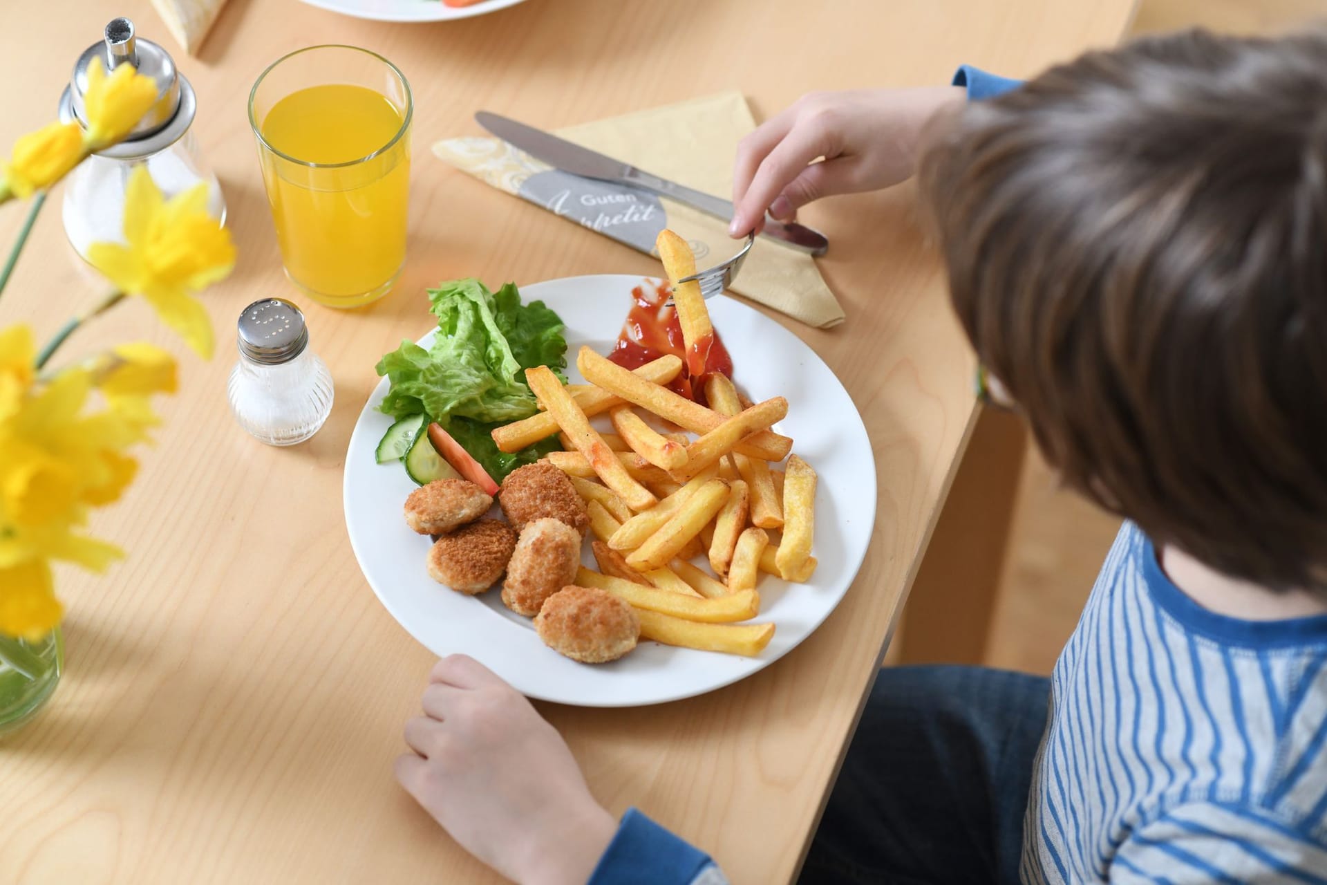 Kind isst Chicken Nuggets und Pommes Frites