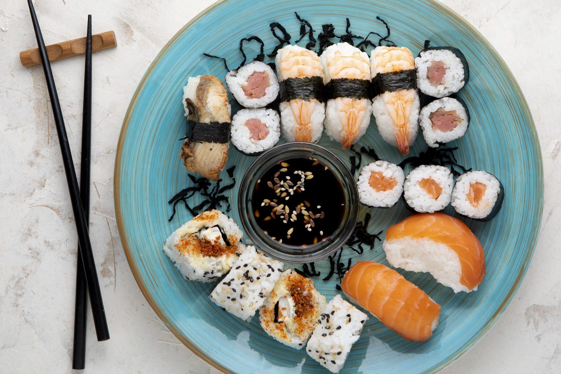 Sushi auf einem Teller, daneben Stäbchen. (Symbolfoto)