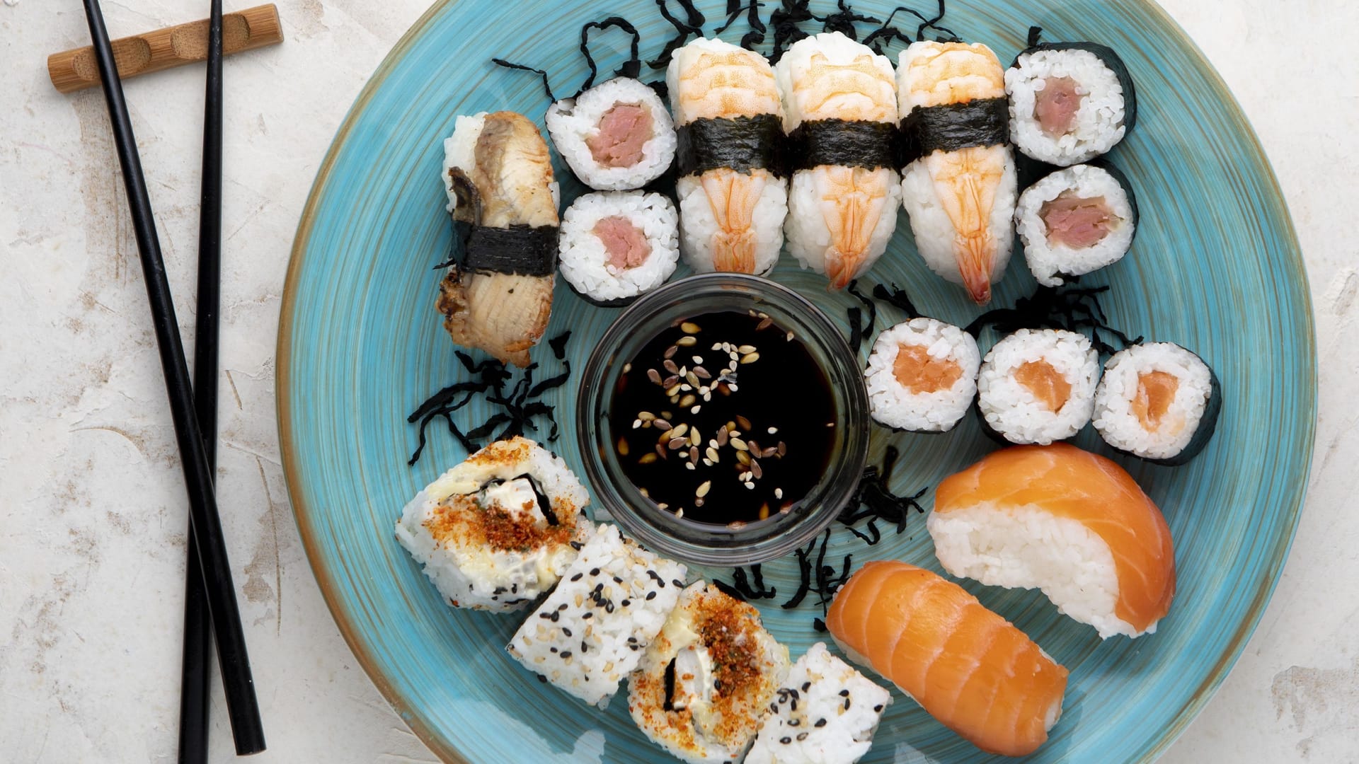 Sushi auf einem Teller, daneben Stäbchen. (Symbolfoto)