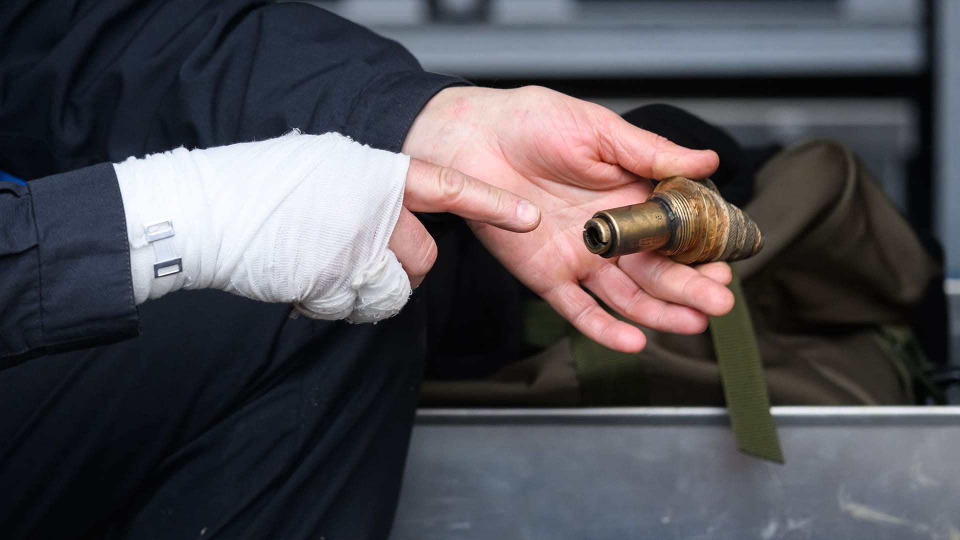 Sprengmeister Thomas Zowalla von der Kampfmittelbeseitigung (KMBD) hockt nach der Entschärfung einer Weltkriegsbombe, die an der Baustraße für den Abriss der Carolabrücke gefunden worden war, hinter dem Sprengkörper und hält dabei den Zünder in der Hand.