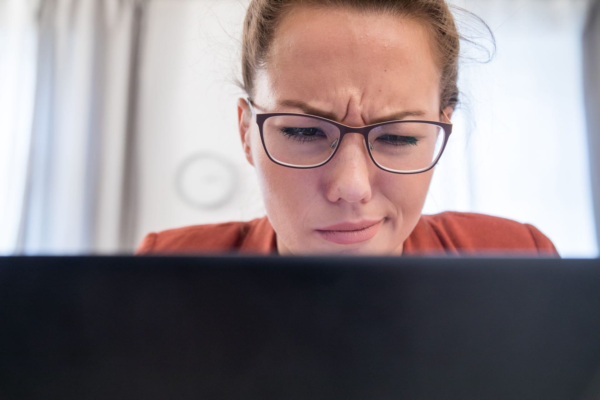 Frau schaut skeptisch auf den Bildschirm ihres Laptops