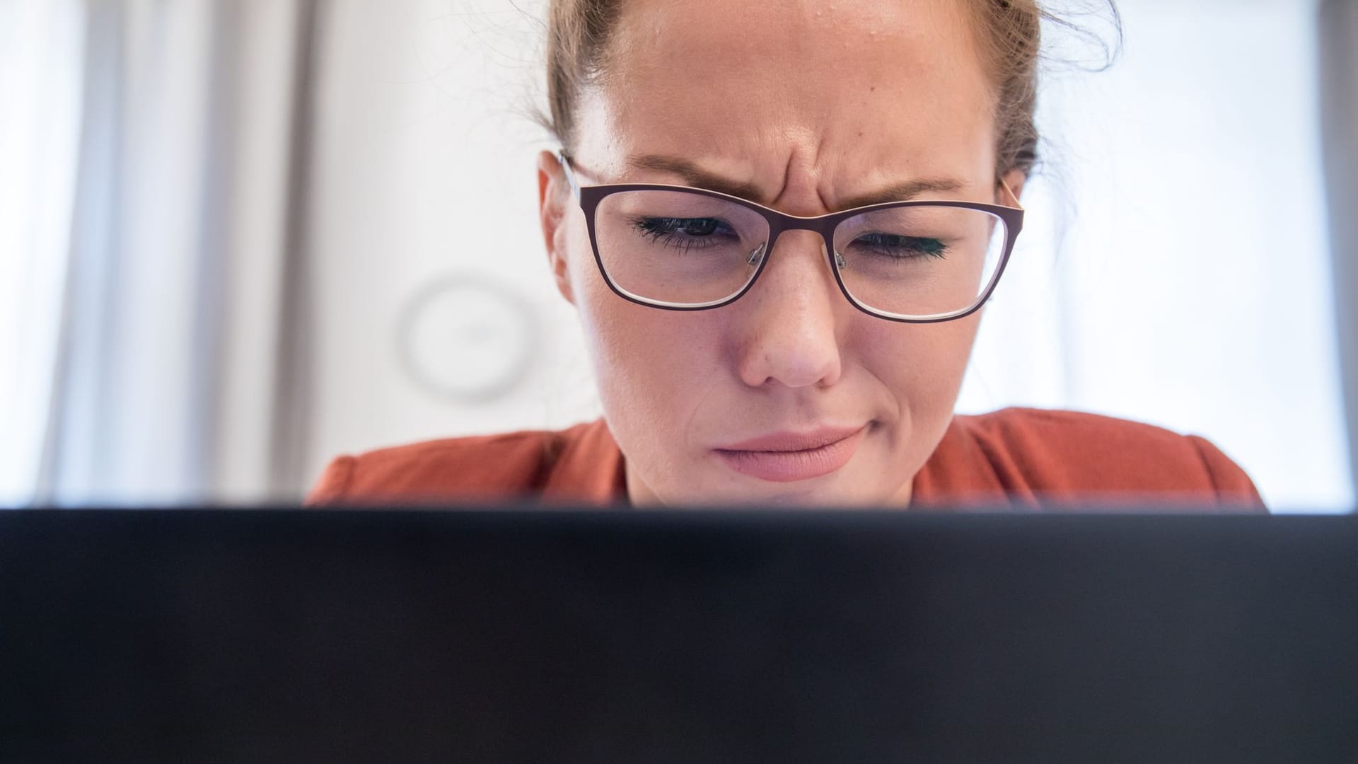 Frau schaut skeptisch auf den Bildschirm ihres Laptops