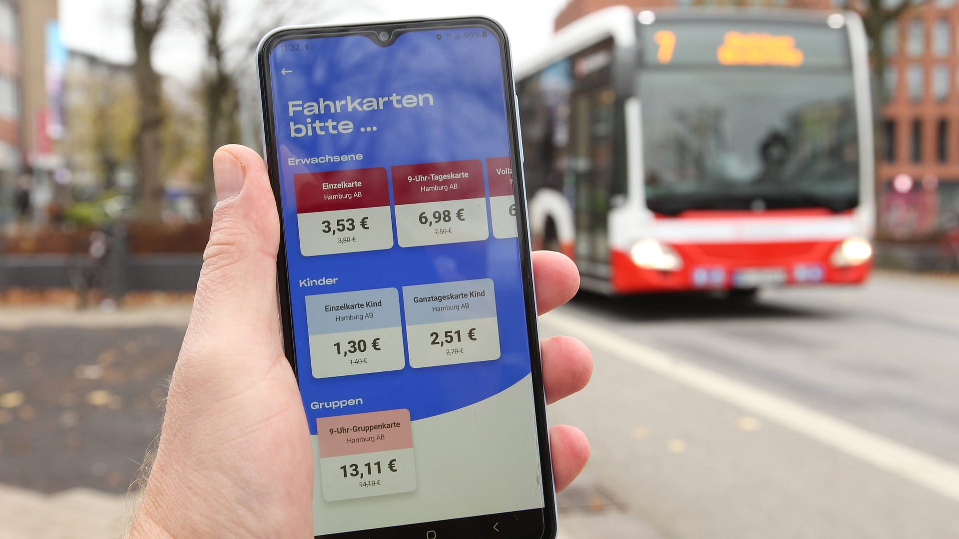 Ein Mann hält an einer Bushaltestelle sein Smartphone in der Hand (Symbolbild): Technische Probleme sorgten am Montag für eine Störung der HVV-App.