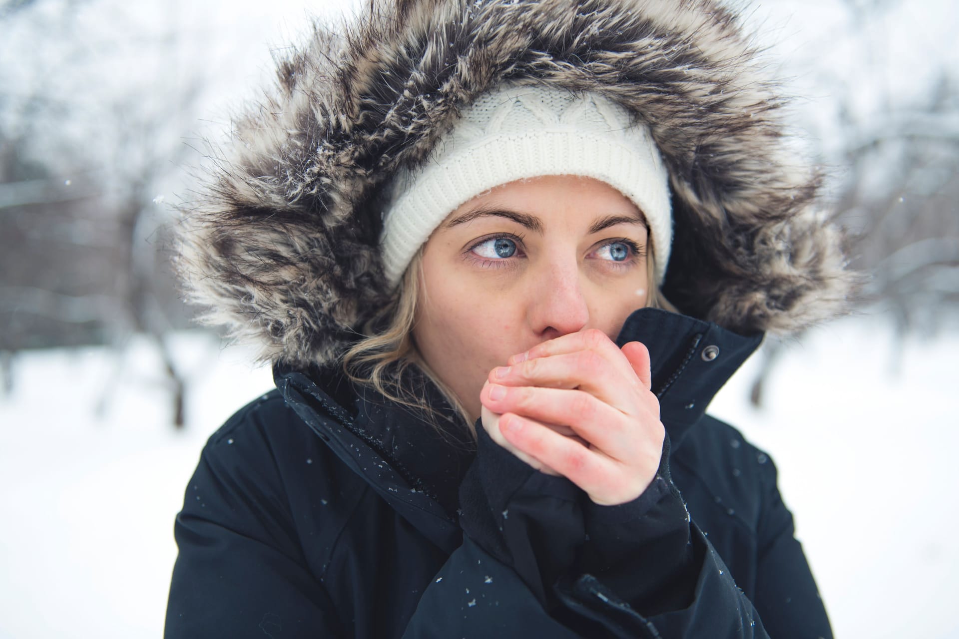 Frau haucht in ihre kalten Hände: Bei feuchtkaltem Wetter können sich mitunter Frostbeulen entwickeln.