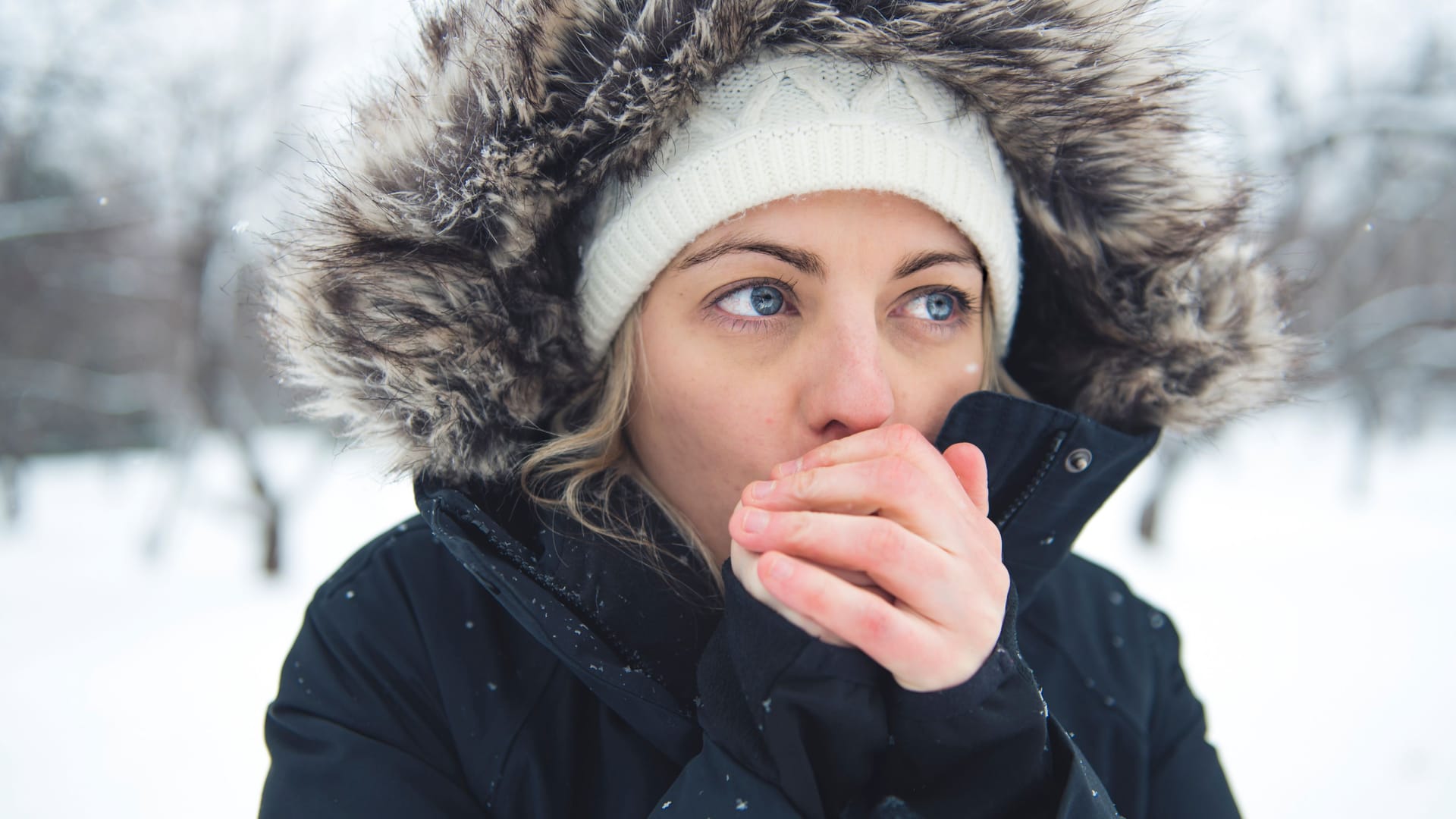 Frau haucht in ihre kalten Hände: Bei feuchtkaltem Wetter können sich mitunter Frostbeulen entwickeln.