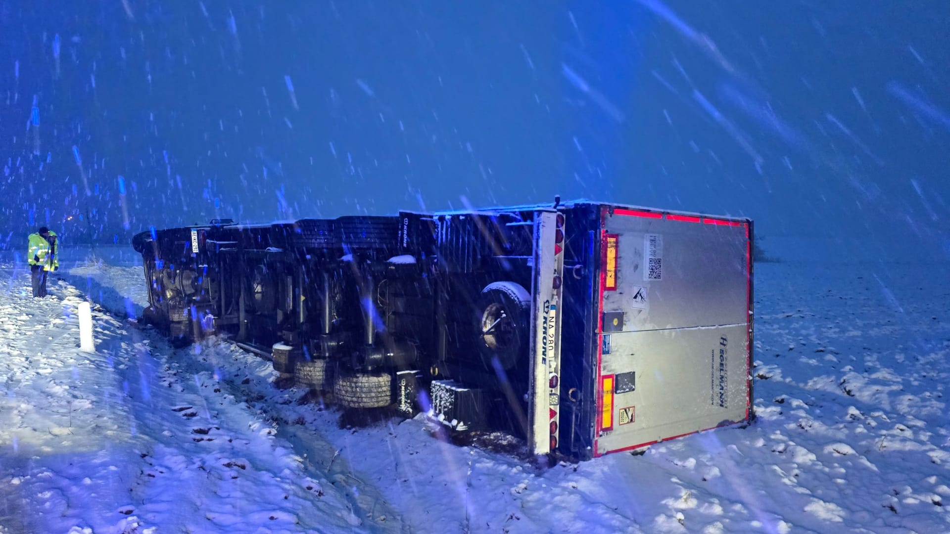 Ein Lastwagen liegt umgekippt neben der Straße. Auf der Landstraße 159 zwischen Wederath und Hinzerath im Hunsrück hat der starke Schneefall zu einem schweren Verkehrsunfall geführt.