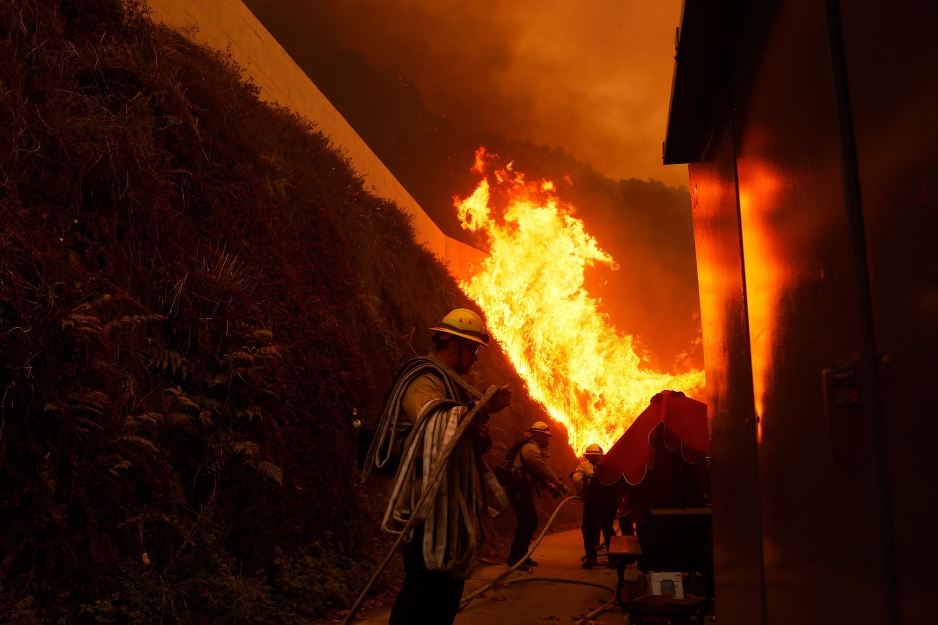 Feuerwehrleute schützen Gebäude vor dem sich ausbreitenden Palisades-Feuer im Stadtteil Pacific Palisades von Los Angeles.