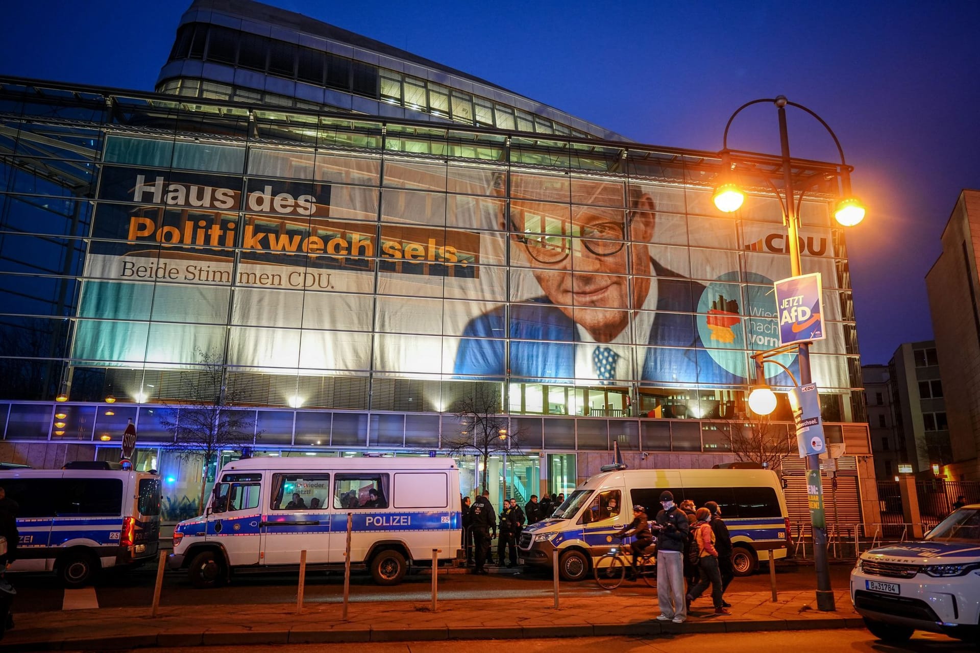 30.01.2025, Berlin: Polizeibeamte bereiten Sicherheitsmaßnahmen vor der CDU-Parteizentrale vor, an deren Fassade ein riesiges Plakat mit F. Merz, CDU-Bundesvorsitzender, Unionsfraktionsvorsitzender und Kanzlerkandidat der Union, hängt. Auf dem Plakat steht der Schriftzug "Haus des Politikwechsels". Der Bundestag hatte am Mittwoch mit Unterstützung der AfD einem Antrag der Union zugestimmt, der Zurückweisungen von Asylsuchenden an den deutschen Grenzen vorsieht. Foto: Kay Nietfeld/dpa