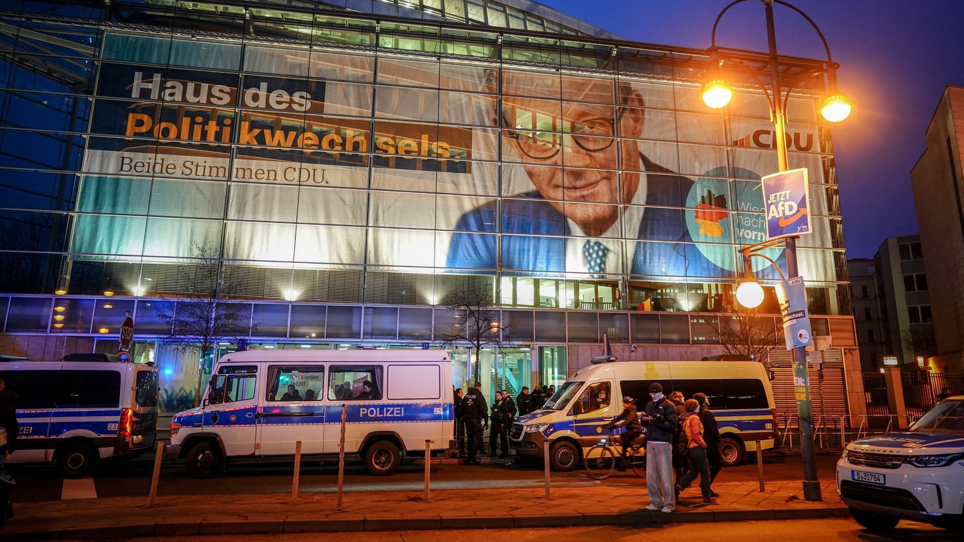 30.01.2025, Berlin: Polizeibeamte bereiten Sicherheitsmaßnahmen vor der CDU-Parteizentrale vor, an deren Fassade ein riesiges Plakat mit F. Merz, CDU-Bundesvorsitzender, Unionsfraktionsvorsitzender und Kanzlerkandidat der Union, hängt. Auf dem Plakat steht der Schriftzug "Haus des Politikwechsels". Der Bundestag hatte am Mittwoch mit Unterstützung der AfD einem Antrag der Union zugestimmt, der Zurückweisungen von Asylsuchenden an den deutschen Grenzen vorsieht. Foto: Kay Nietfeld/dpa