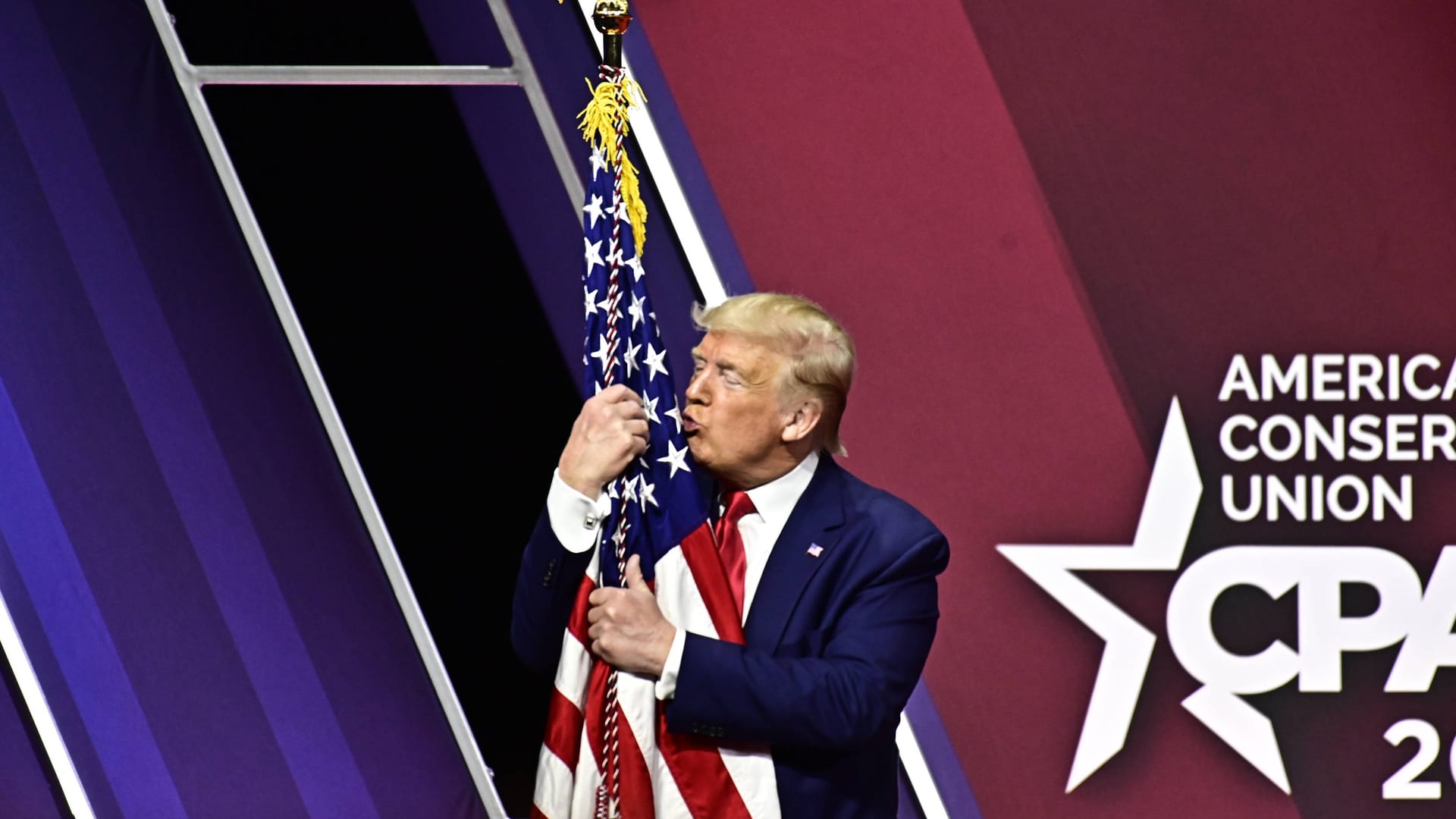 Donald Trump in liebevoller Umarmung mit der amerikanischen Flagge.