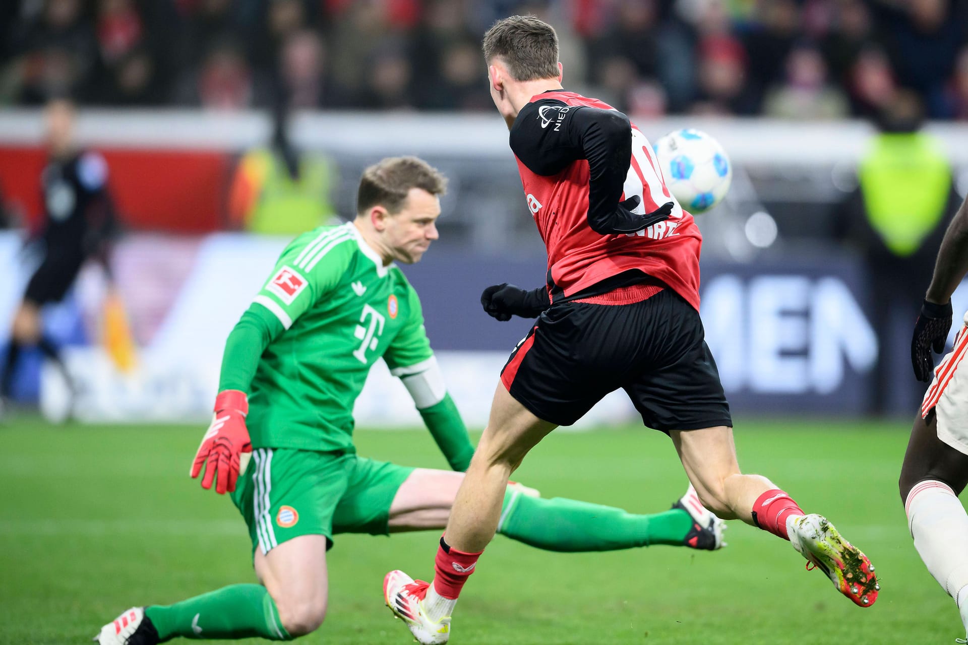 Schwerstarbeit: Bayerns Manuel Neuer (li.) klärt gegen Leverkusens Florian Wirtz.