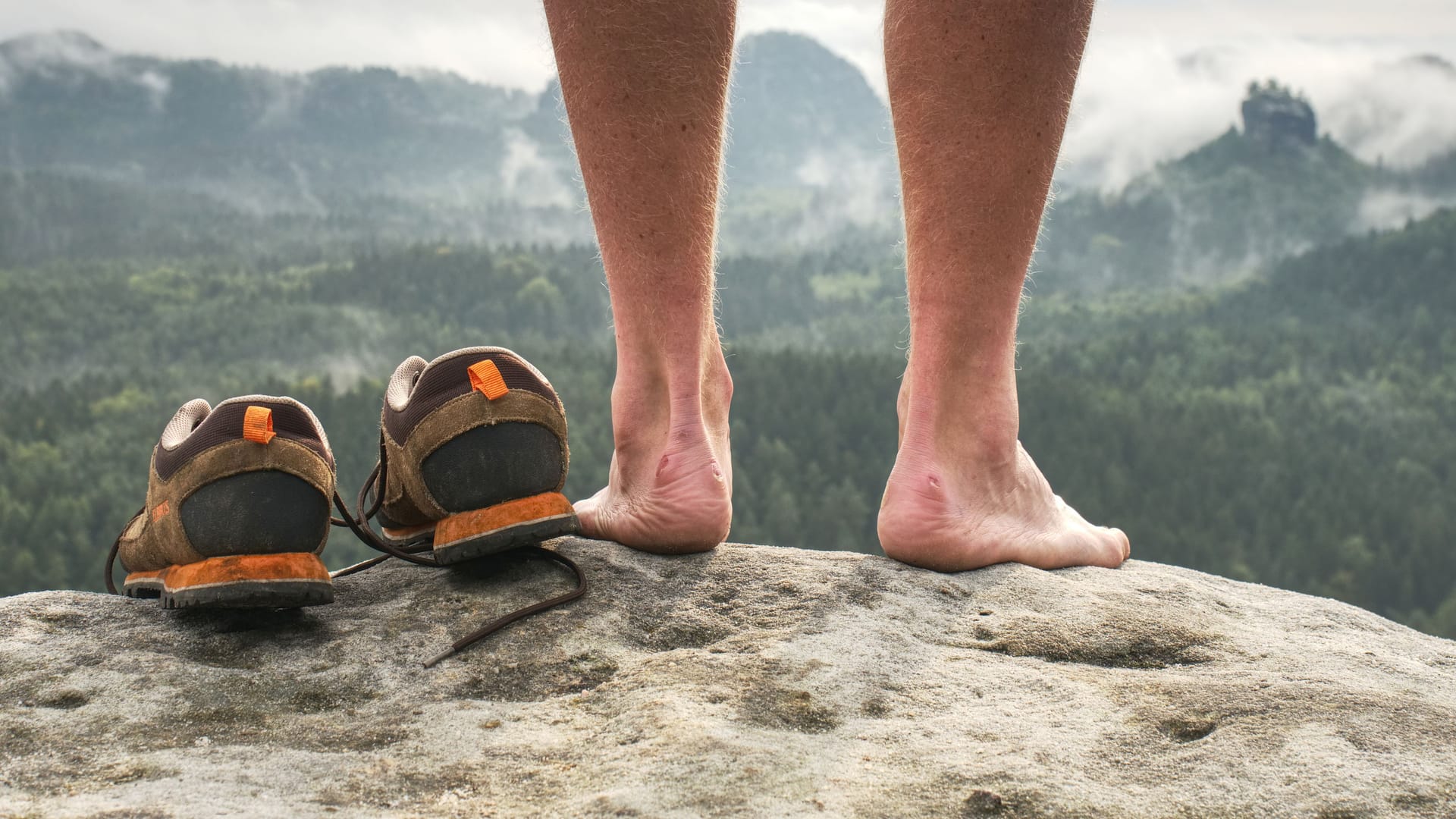 Nackte Füße neben einem Paar Wanderschuhe: