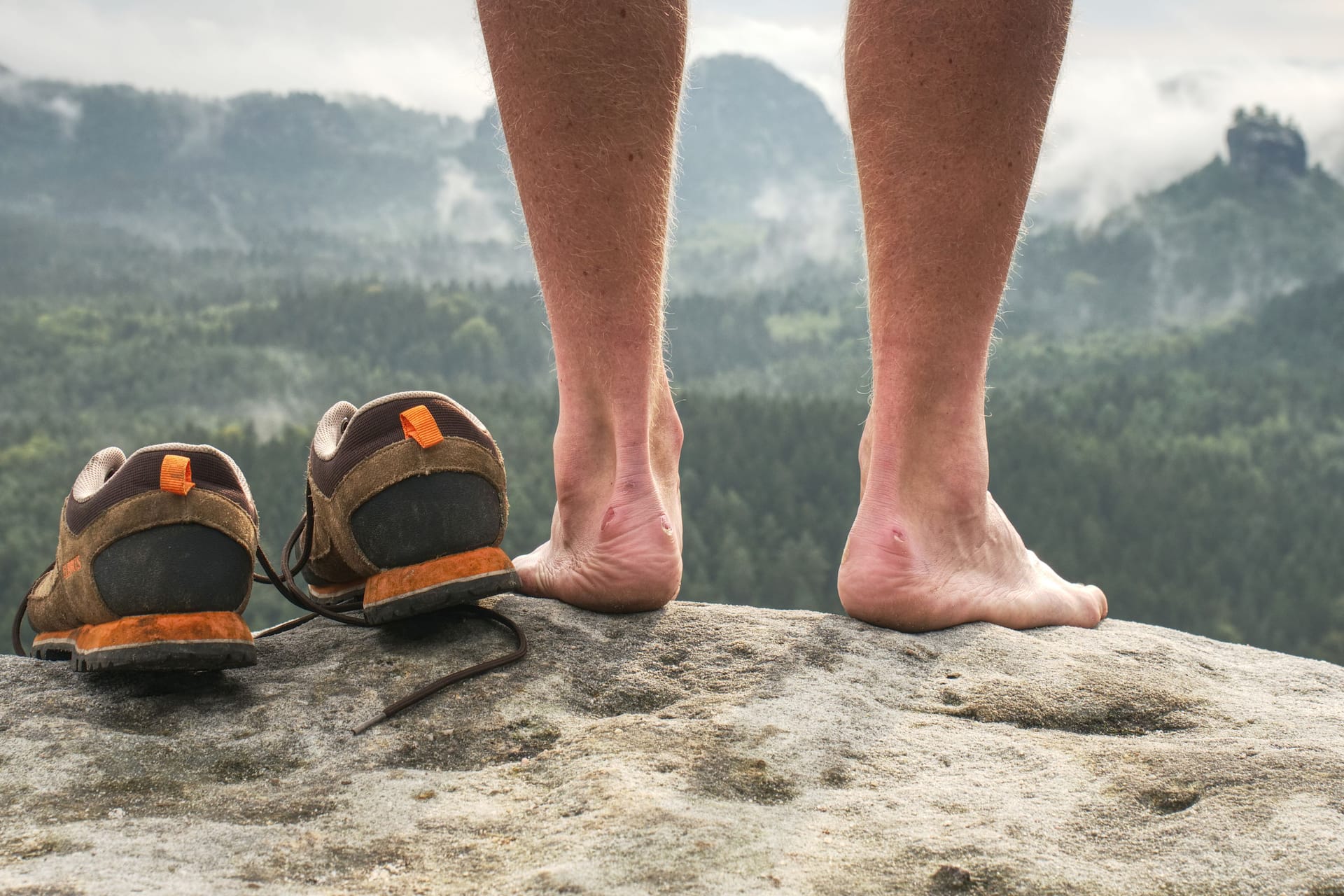 Nackte Füße neben einem Paar Wanderschuhe: