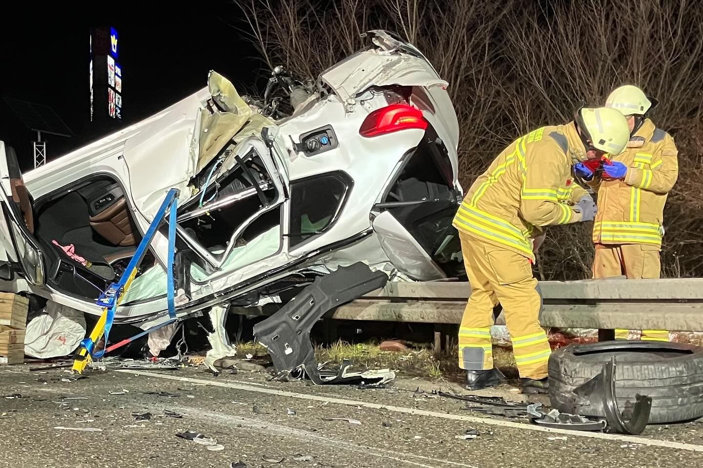 Feuerwehrleute am Unfallort: Der BMW-Fahrer wurde aus dem Auto geschleudert und unter dem Fahrzeug eingeklemmt.