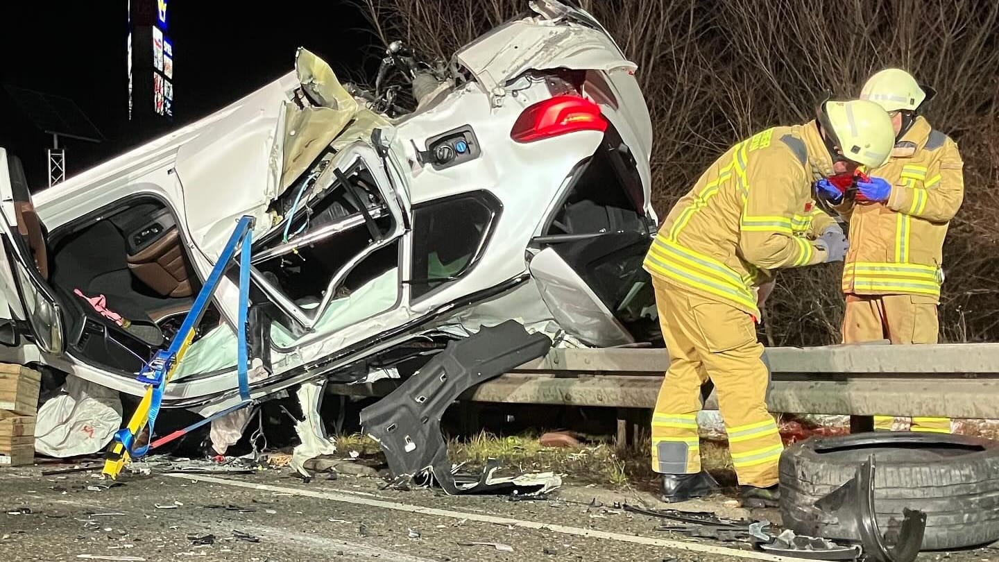 Feuerwehrleute am Unfallort: Der BMW-Fahrer wurde aus dem Auto geschleudert und unter dem Fahrzeug eingeklemmt.